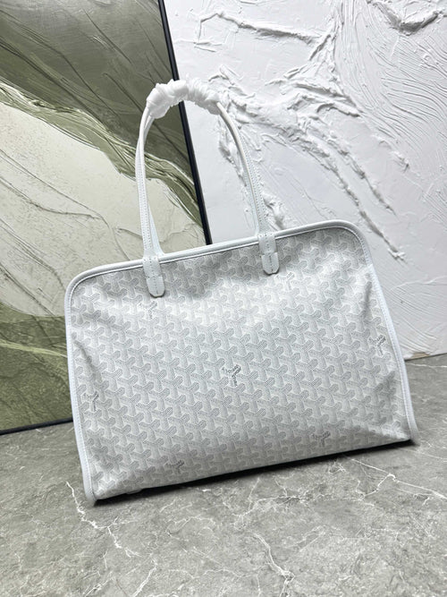 Silver textured handbag on a marble surface with a white textured wall in the background